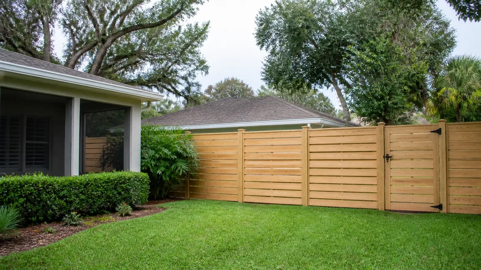 A horizontal cedar privacy fence behind a mown lawn and hedges